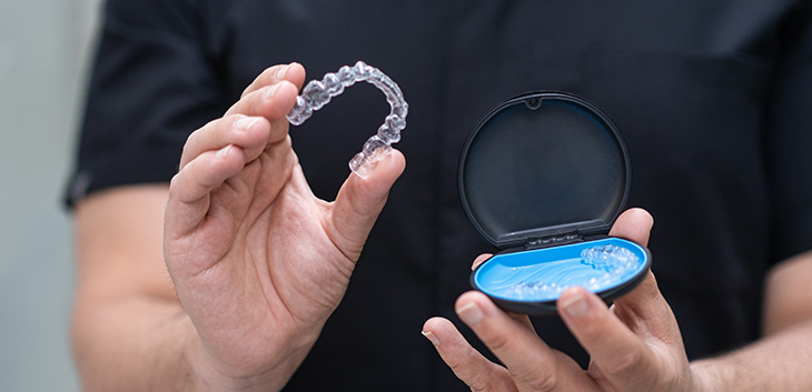 hands holding aligners and aligner case