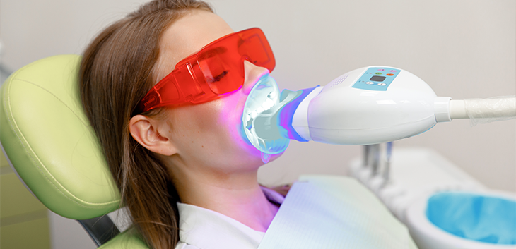 teeth whitening light being shined on woman's teeth