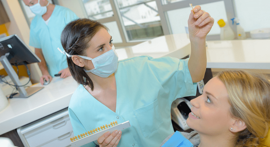 Masked dental hygienist treating a patient reclined in the chair