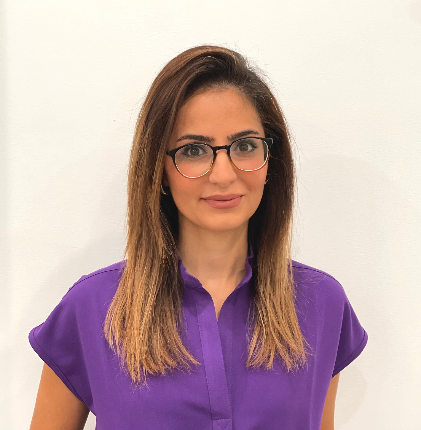 Portrait of Dr. Fatemeh Arabpour in a purple top against a plain white wall