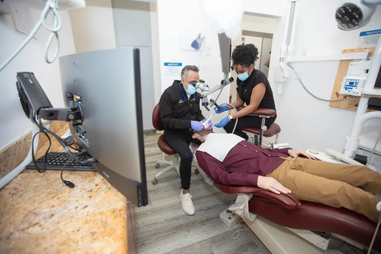 Dr. Kourosh Yousefzadeh and an assistant treating a patient under the surgical microscope