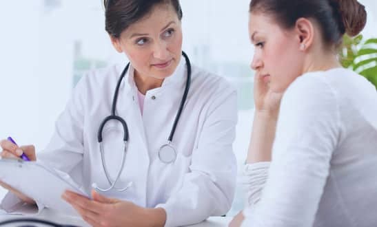 Clinician in a white coat going through notes with a patient