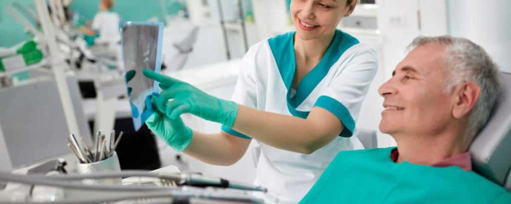 Clinician showing a dental scan on a tablet to a patient in the chair