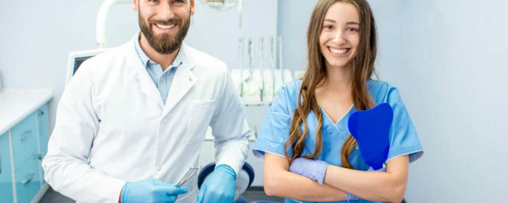 Dentist and dental assistant standing together in a treatment room