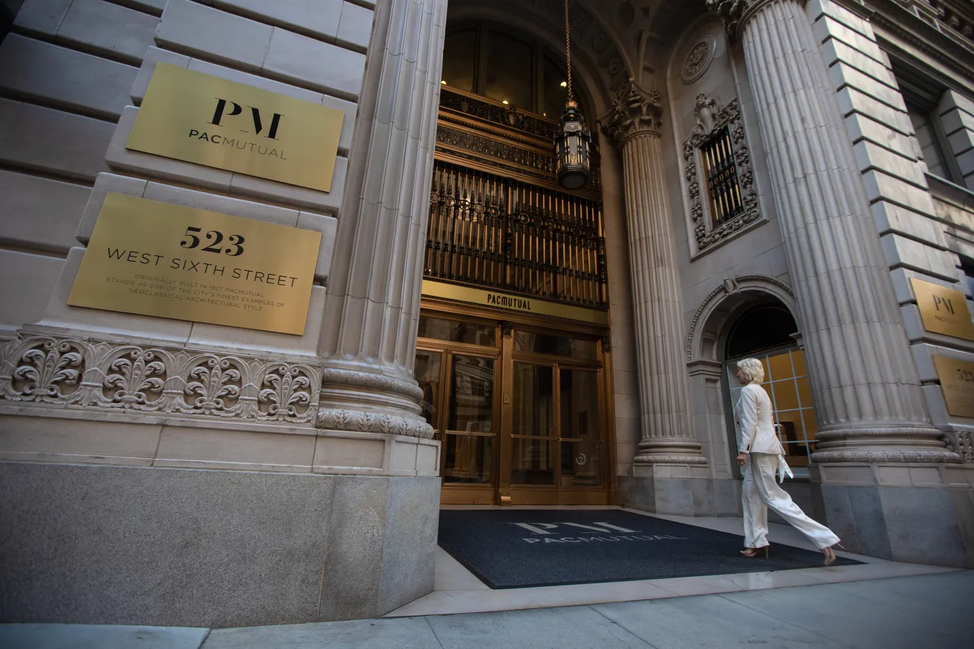 The Pacific Mutual building entrance at 523 West Sixth Street, brass plaques beside the doors and a patient walking in