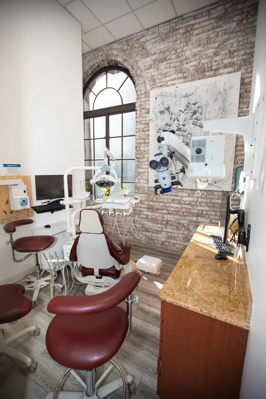 An operatory equipped with a surgical microscope beside the exposed brick wall