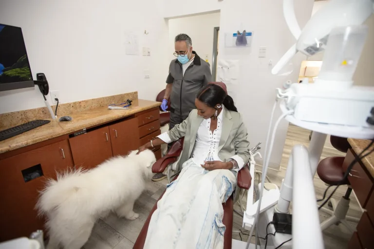 A patient in a treatment room with the practice dog beside the chair