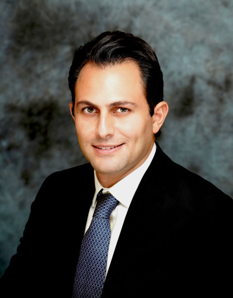 Studio portrait of Dr. Nariman Saadat in a dark suit and blue patterned tie