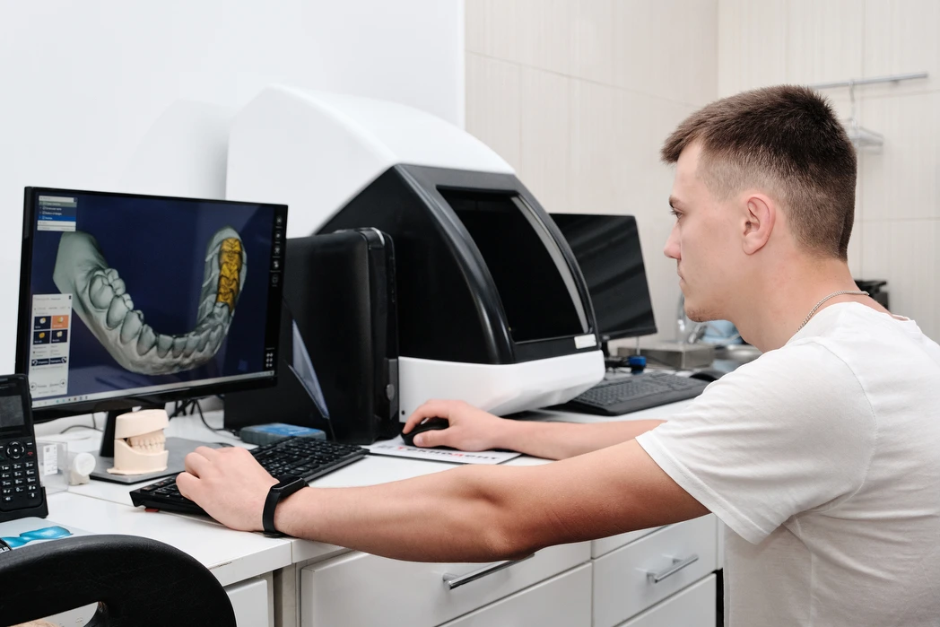 A technician designing a restoration on screen beside a milling unit