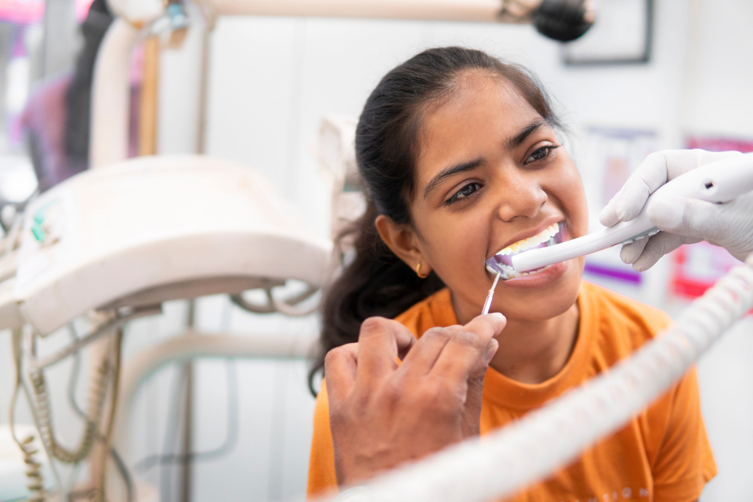 A patient holding a mirror while a clinician uses an intraoral camera
