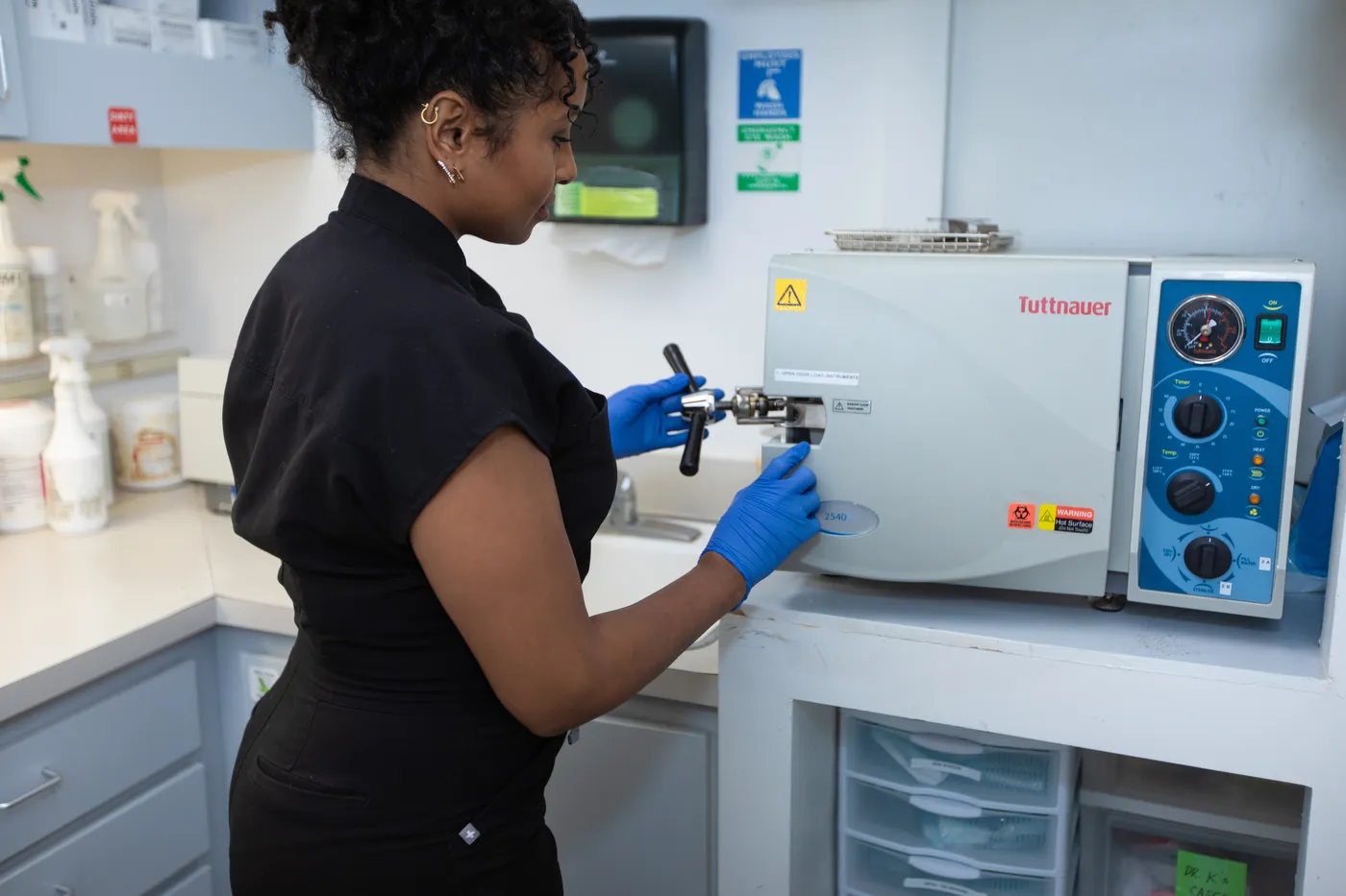 A team member loading instruments into the autoclave in the sterilization room
