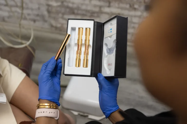 Gloved hands holding an open take-home whitening kit